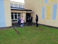Policjantka rozdaje elementy odblaskowe uczniom klasy pierwszej przy tylnym wejściu do szkoły, przy ul. Osmolińskiej w Zduńskiej Woli