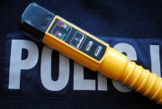 Żółte urządzenie alcoblow leży na bluzie granatowej z napisem policja