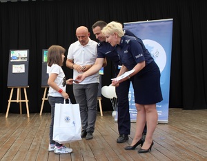 Dziewczynka odbiera nagrodę od inspektora Małgorzaty Mączyńskiej Komendanta Powiatowego Policji w Zduńskiej Woli