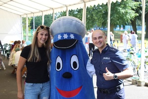 Zdjęcie policjanta i kobiety obok maskotki Komisarz Błysk