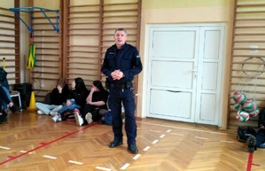 Policjant na szkolnej sali gimnastycznej, mówi młodzieży o handlu ludźmi.