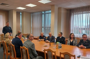 Przy stole siedzą goście, w szczycie stołu stoi zastępca komendanta młodszy inspektor Benedykt Andrzejak
