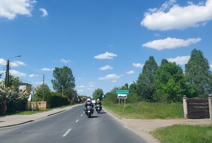 Droga, jadą dwa policyjne motocykle, po prawej stronie znak drogowy z napisem Zduńska Wola